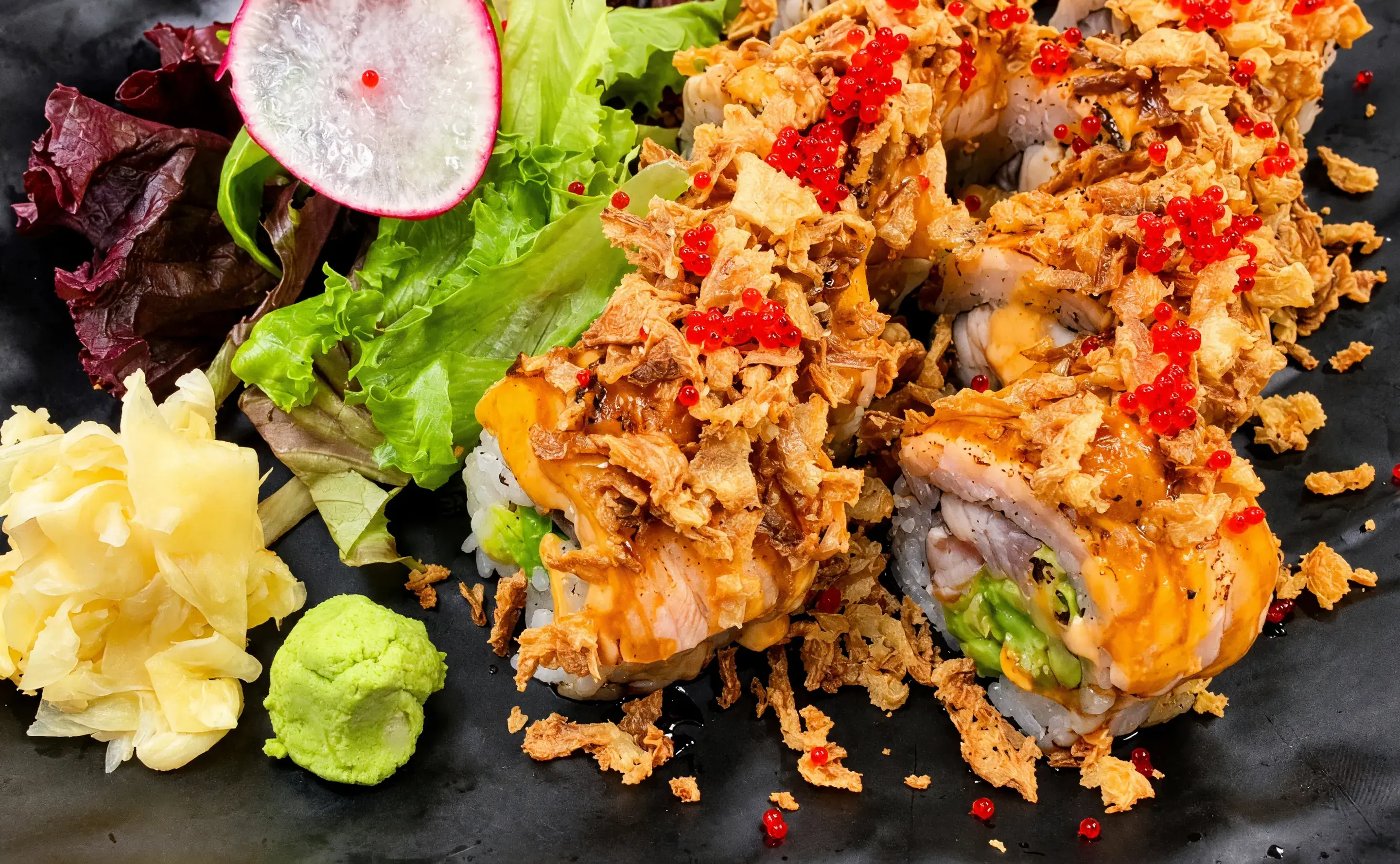 Double Salmon Roll with torched salmon, crispy onion and red tobiko, beside ginger, wasabi and salad
