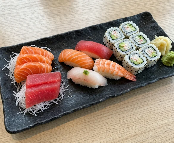Sashimi Sushi Combo: salmon and tuna sashimi, four nigiri and California roll on a black plate